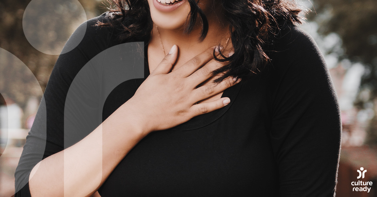 Close up of a woman with a hand placed over her heart.